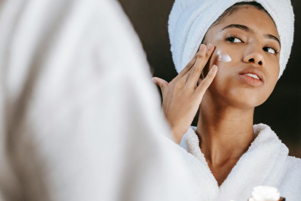 Woman in a bathrobe practices her skincare routine with How to Achieve Glowing Skin: Expert Tipsmoisturizing cream. Perfect for wellness themes.