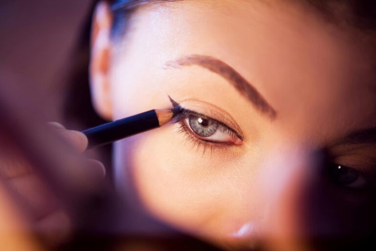 A close-up shot of a woman applying eyeliner with precision. best beauty parlour course in Navi Mumbai