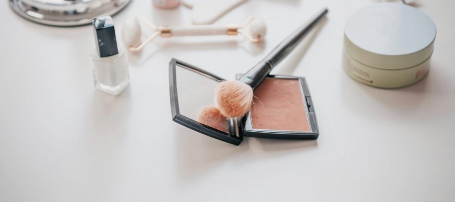 pexels-photo-9218729-9218729 Image of makeup essentials including brushes, compacts, and creams on a vanity table.